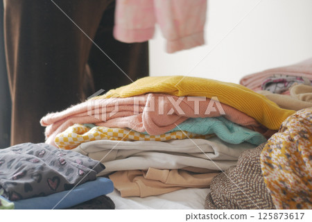 Folding colorful clothes on a bed during a weekend chore Folding colorful clothes on a bed during a weekend chore 125873617