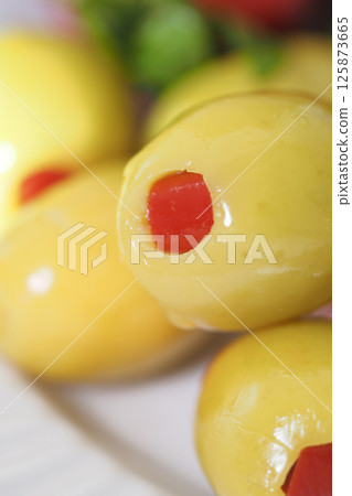 Yellow olives stuffed with red pimento on a wooden platter 125873665