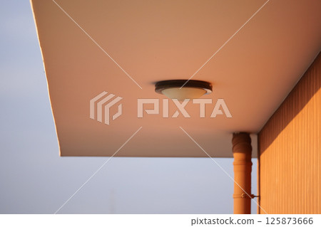 Light fixture under a modern building overhang at sunset 125873666