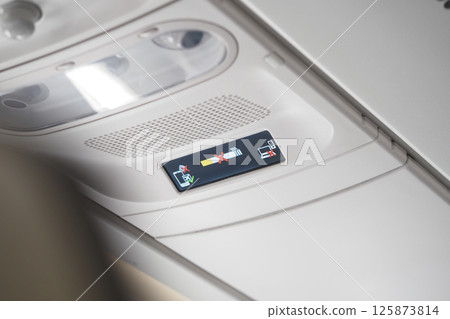 Safety instructions displayed on airplane cabin ceiling 125873814