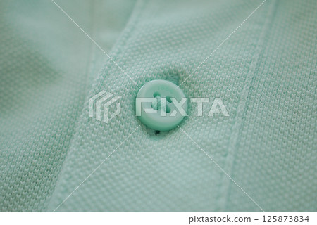 Close-up of a mint green button on textured fabric Close-up of a mint green button on textured fabric 125873834
