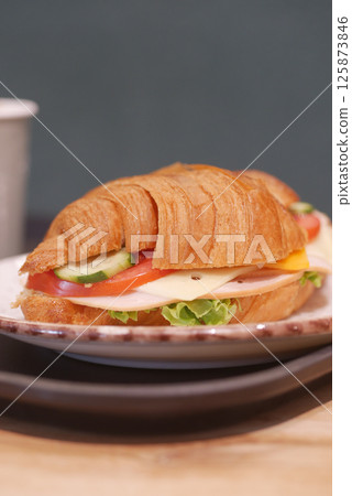 Croissant sandwich with vegetables and cheese on a plate 125873846