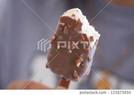 Delicious chocolate-covered ice cream bar with bites taken out 125873850