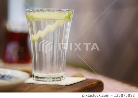 Crisp water with cucumber garnish served in clear glass Crisp water with cucumber garnish served in clear glass 125873858