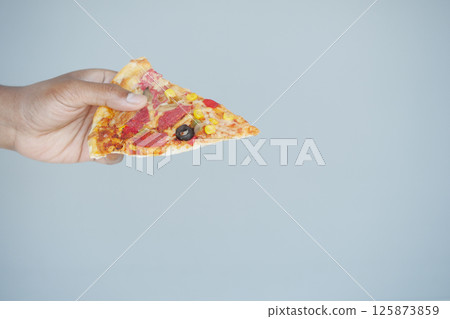 Enjoying a slice of pizza held in hand against a plain background Enjoying a slice of pizza held in hand against a plain background 125873859