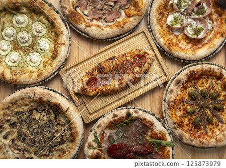 Assortment of traditional italian wood fired pizzas on table 125873979