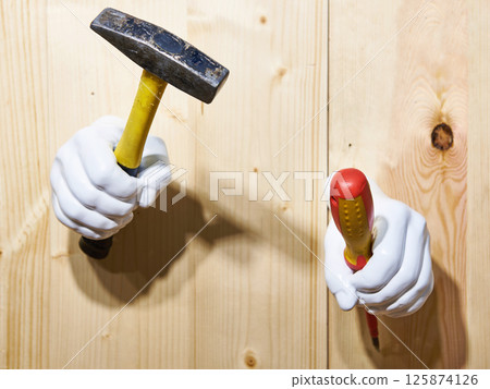 Hand with hammer and screwdriver on wooden wall 125874126
