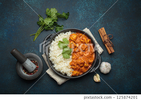 Indian dish chicken tikka masala served with rice and spices on dark blue background top view Indian dish chicken tikka masala served with rice and spices on dark blue background top view 125874201