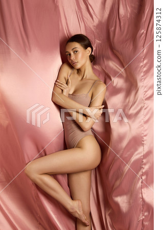 beautiful young woman on a silk background. pretty brunette girl in underwear 125874312