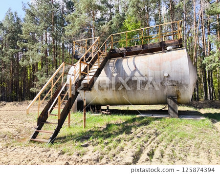 horizontal steel tank. large metal barrel with a ladder in the forest area horizontal steel tank. large metal barrel with a ladder in the forest area 125874394
