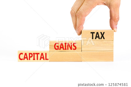 Capital gains tax symbol. Concept words Capital gains tax on beautiful wooden block. Businessman's hand. Beautiful white background. Business and capital gains tax concept. Copy space. Capital gains tax symbol. Concept words Capital gains tax on beautiful wooden block. Businessman's hand. Beautiful white background. Business and capital gains tax concept. Copy space. 125874581