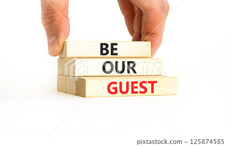Be our guest symbol. Concept words Be our guest on beautiful wooden block. Businessman's hand. Beautiful white background. Business and be our guest concept. Copy space. 125874585