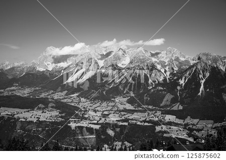 Mountains rise majestically in the background, showcasing the Dachstein range from the vantage point of Planai. The lush valleys below contrast beautifully with the rugged peaks. Mountains rise majestically in the background, showcasing the Dachstein range from the vantage point of Planai. The lush valleys below contrast beautifully with the rugged peaks. 125875602