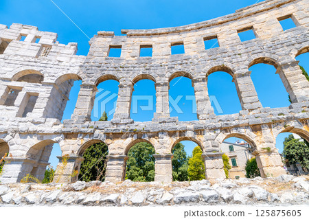 This remarkable Roman amphitheatre in Pula showcases its grand arches against a bright blue sky. Visitors can imagine the vibrant history of events that once took place here. This remarkable Roman amphitheatre in Pula showcases its grand arches against a bright blue sky. Visitors can imagine the vibrant history of events that once took place here. 125875605