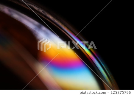 Bright rainbow reflection of liquid on black background, red colours, surrealistic pattern 125875796