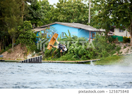 Man Wakeboarding Mid-Air Trick Over Obstacle Ramp 125875848