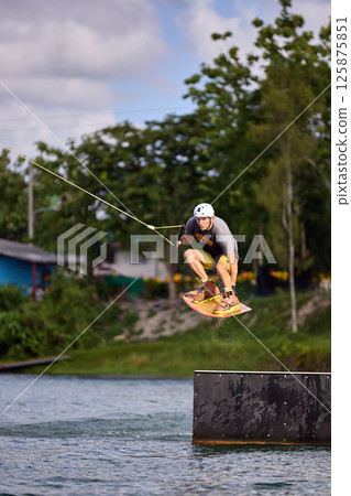 Man Wakeboarding Mid-Air Trick Over Obstacle Ramp Man Wakeboarding Mid-Air Trick Over Obstacle Ramp 125875851