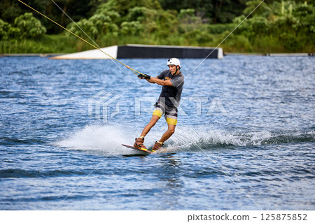 Wakeboarder Riding on Water Holding Tow Rope Wakeboarder Riding on Water Holding Tow Rope 125875852