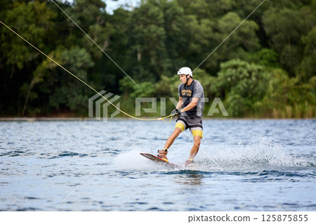 Wakeboarder Riding on Water Holding Tow Rope 125875855