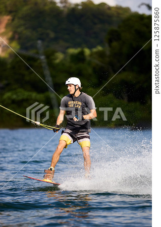 Wakeboarder Riding on Water Holding Tow Rope 125875860