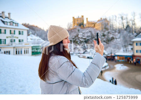 Joyful Winter Selfie Woman Smiling in Snowy Landscape Capturing Fun Moment with Smartphone Surrounded by Scenic Winter Wonderland 125875999