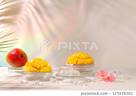 Modern minimal still life with exotic mango fruit on sunny table with palm tree shadows,summer holiday concept.Summer banner with tropical fruits,vegan food for weight loss 125876302