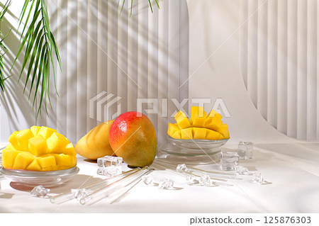 Modern minimal still life with exotic mango fruit on sunny table with palm tree shadows,summer holiday concept.Summer banner with tropical fruits,vegan food for weight loss 125876303