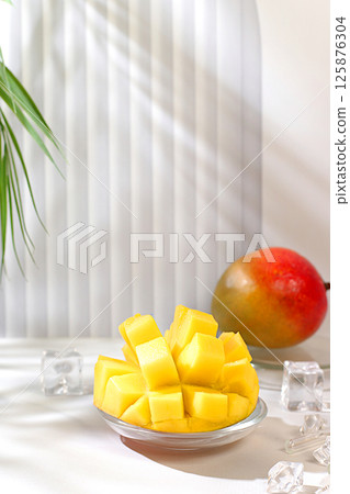 Modern minimal still life with exotic mango fruit on sunny table with palm tree shadows,summer holiday concept.Summer banner with tropical fruits,vegan food for weight loss 125876304