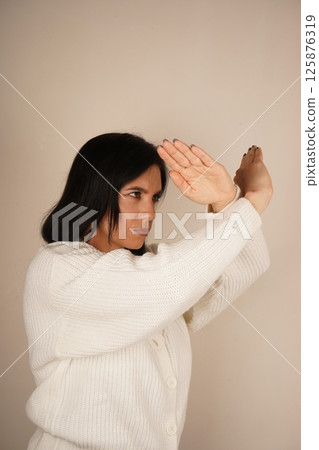 The gesture shows determination and resolve. A woman crosses her arms in front of her, fists clenched, signaling readiness for protection. Her posture conveys a sense of defense and strength. 125876319