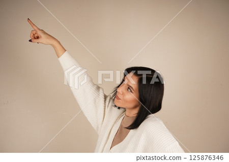 A gesture full of purpose and clarity. The young woman points in one direction with both index fingers, clearly indicating a path. Her posture is confident and expressive. A gesture full of purpose and clarity. The young woman points in one direction with both index fingers, clearly indicating a path. Her posture is confident and expressive. 125876346