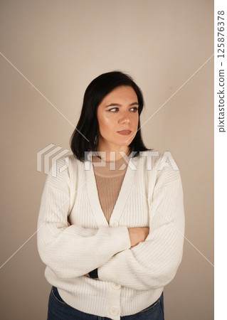 A woman arms crossed on her breast, symbolizing confidence and perseverance. Her posture conveys unwavering commitment. The woman stands confidently and smiling. 125876378