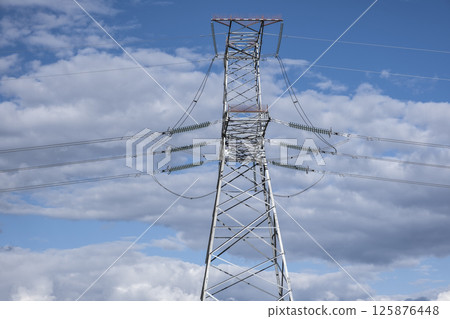 Tower of a high-voltage power line against the of blue sky and clouds Tower of a high-voltage power line against the of blue sky and clouds 125876448