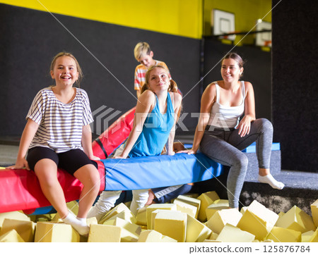 Group of excited active kids having fun while spending their weekend at indoor playground trampoline center Group of excited active kids having fun while spending their weekend at indoor playground trampoline center 125876784