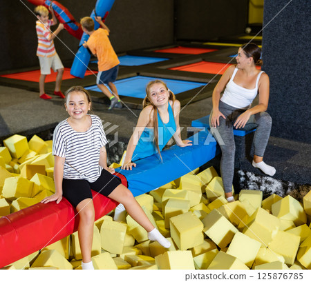 Cheerful teen sisters spending time in pool with foam cubes Cheerful teen sisters spending time in pool with foam cubes 125876785