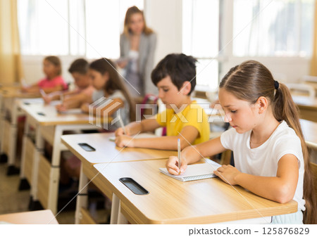 Schoolgirl sitting in classroom during lesson in elementary school Schoolgirl sitting in classroom during lesson in elementary school 125876829