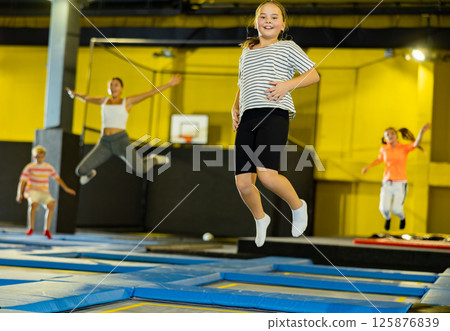 Tween girl having fun jumping in indoor trampoline arena 125876839