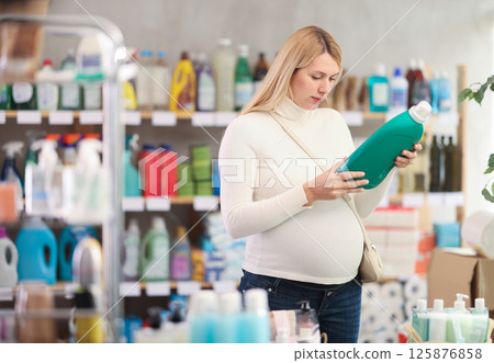 Interested pregnant woman choosing safe laundry detergent in store 125876858