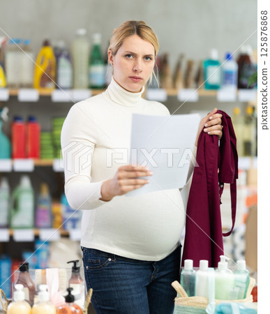 Distressed pregnant store worker reading termination papers Distressed pregnant store worker reading termination papers 125876868