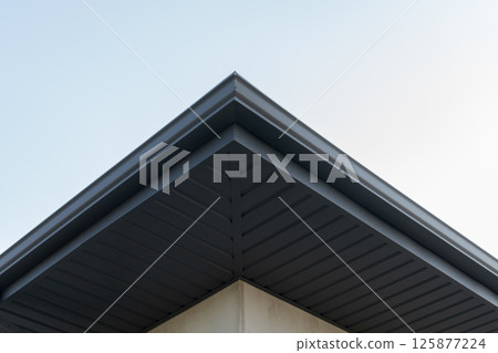 Architectural detail of a contemporary building with a sharp roof line contrasted by the morning sky's soft hues Architectural detail of a contemporary building with a sharp roof line contrasted by the morning sky's soft hues 125877224