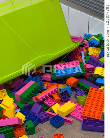 Brightly colored plastic building blocks are scattered across the floor, inviting children to build and explore their creativity Brightly colored plastic building blocks are scattered across the floor, inviting children to build and explore their creativity 125877293