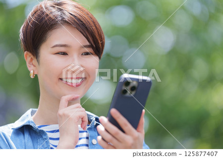 A woman looking at a smartphone thinking A woman looking at a smartphone thinking 125877407