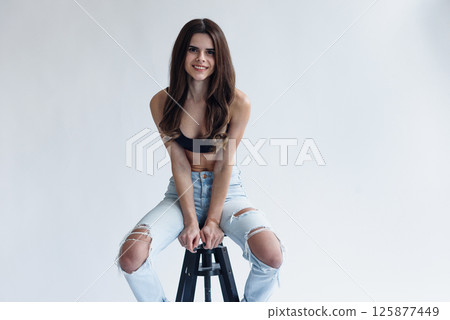 Charming skinny beautiful girl with perfect abs in jeans and black top isolated on gray background 125877449