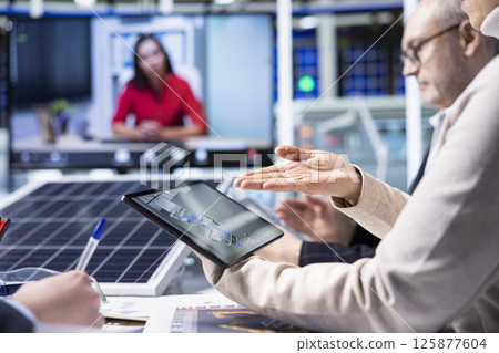 Factory experts design assembly facility production lines in tablet CAD program in videoconference. Employees use software on device to optimize factory production layouts in internet videocall 125877604