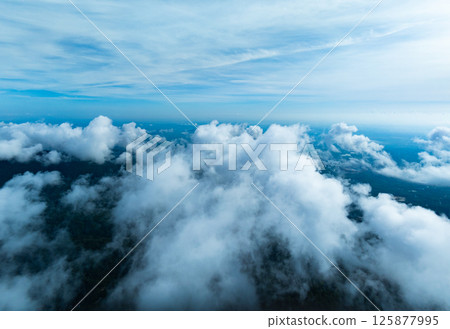 Aerial view drone shot of flowing fog waves on mountain tropical rainforest,Bird eye view image over the clouds Amazing nature background with clouds and mountain peaks 125877995