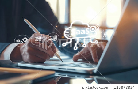 Business Professional Illustrating Software as a Service (SaaS) Concept with Laptop and Cloud Computing Symbols in Modern Office Environment XDMCP 125878834