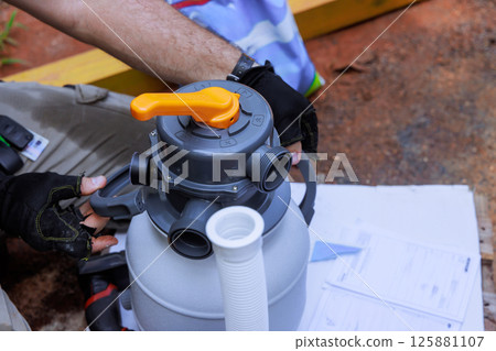 Technician worker is analyzing swimming pump filter system at home, preparing for pool maintenance 125881107