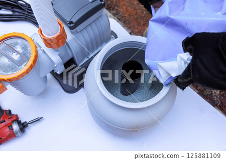 Assembling components of pool filtration system on works day in backyard setting, near swimming pool 125881109