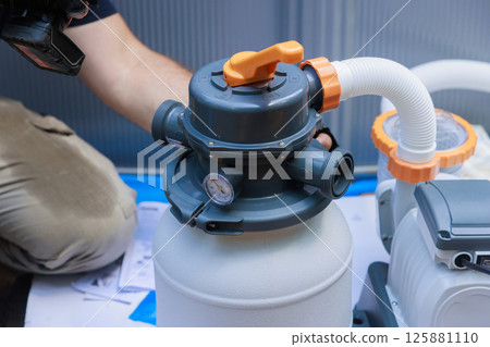 Plumber is installing pool filter system, checking connections gauges in backyard environment. Plumber is installing pool filter system, checking connections gauges in backyard environment. 125881110