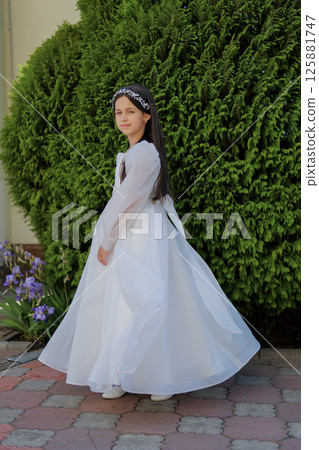 The child stands in a light dress. The ivory outfit creates an image of spiritual purity. 125881747