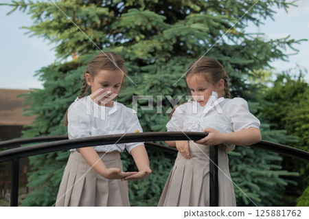 Twins are focused on a little forest guest. Their hairstyles and outfits create a sense of purity and unity. Twins are focused on a little forest guest. Their hairstyles and outfits create a sense of purity and unity. 125881762